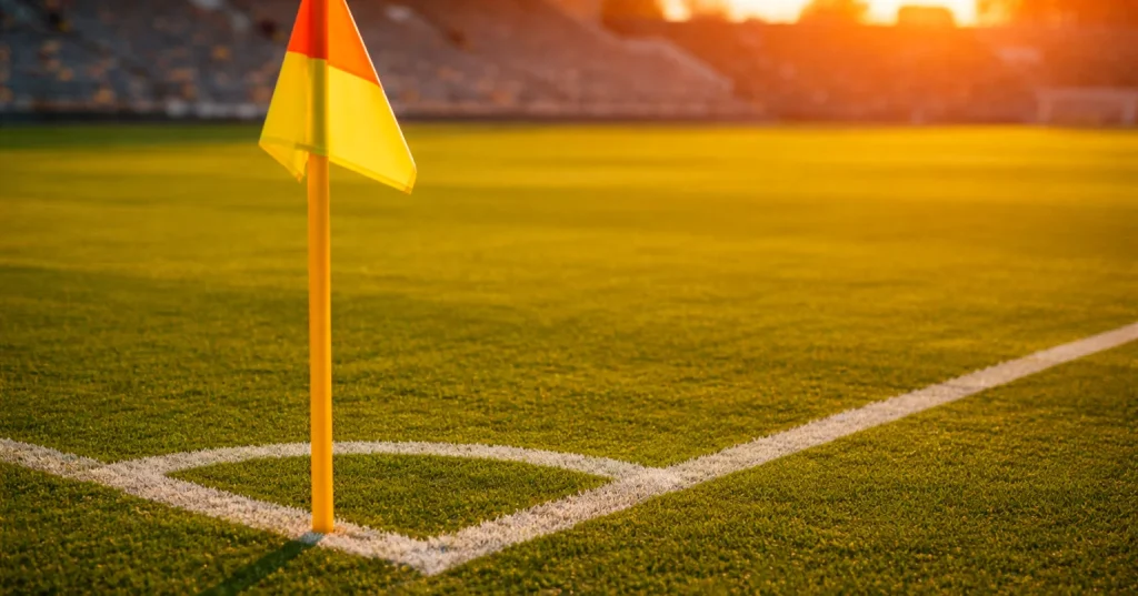Bandeirinha de canto num campo de futebol relvado ao entardecer